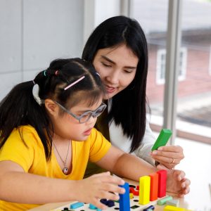 Girl With Down's Syndrome Play Puzzle Toy With Her Teacher.