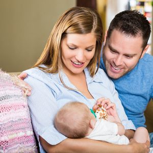 New Parents Staring At Newborn Baby Daughter At Home